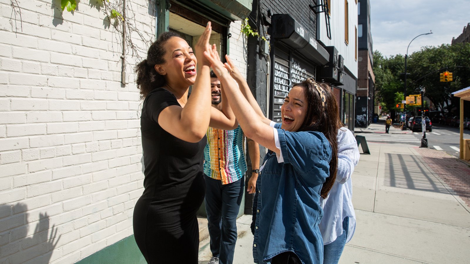 August pals Tirzah Enumah and Alexis Gonzales-Black high-five each other on a New York sidewalk.