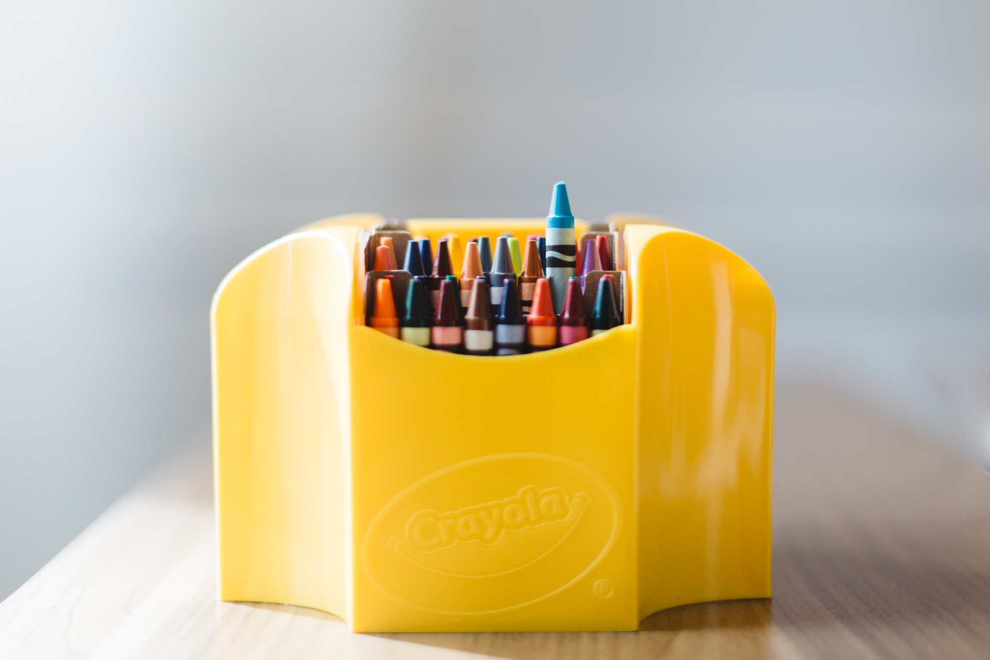 “Yellow box of crayons sit on a wooden table” by Evan Kirby