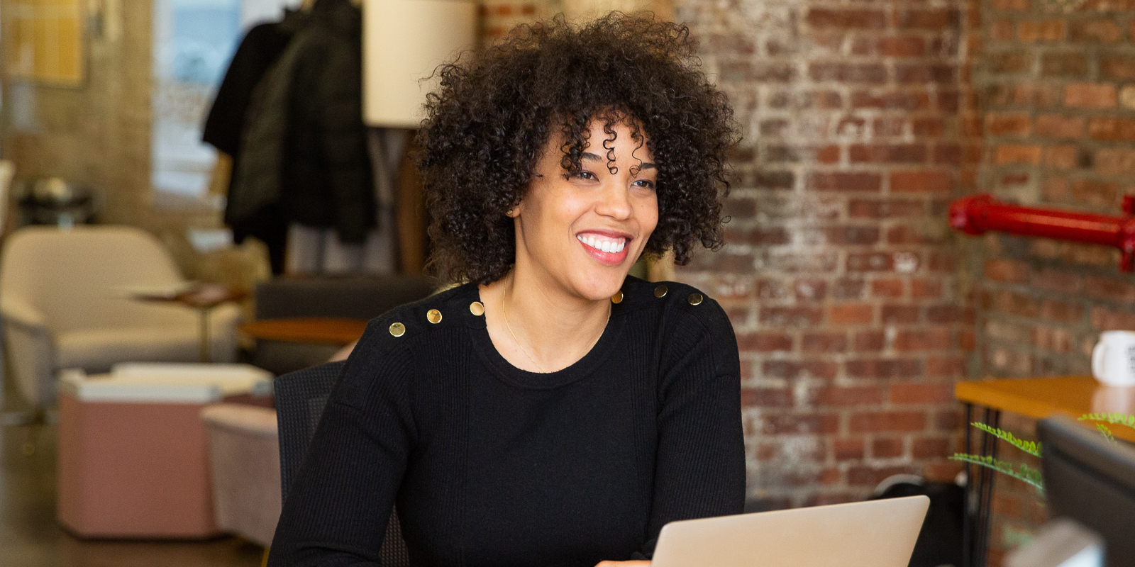 August pal Tirzah Enumah smiles at a colleague (off camera) in a Brooklyn conference room.